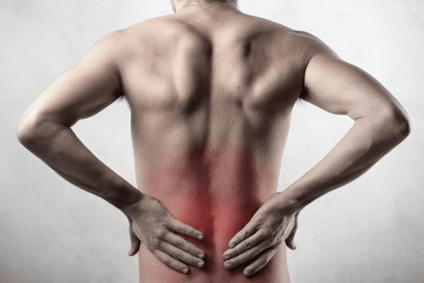 Male with low back pain, holding his low back with both hands, with a red glow to show the area of pain